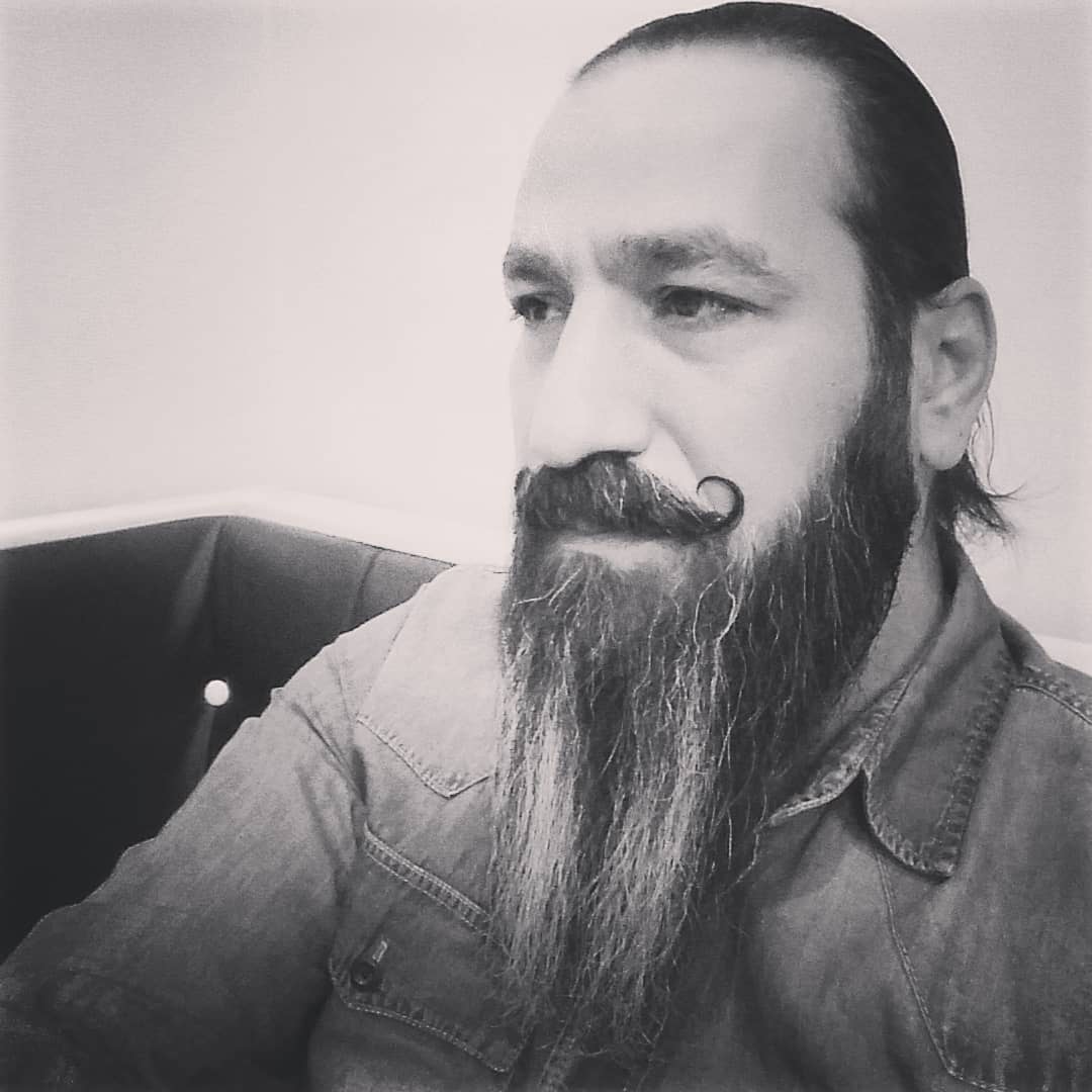Ziad i profil med långt helskägg och tvinnad mustasch